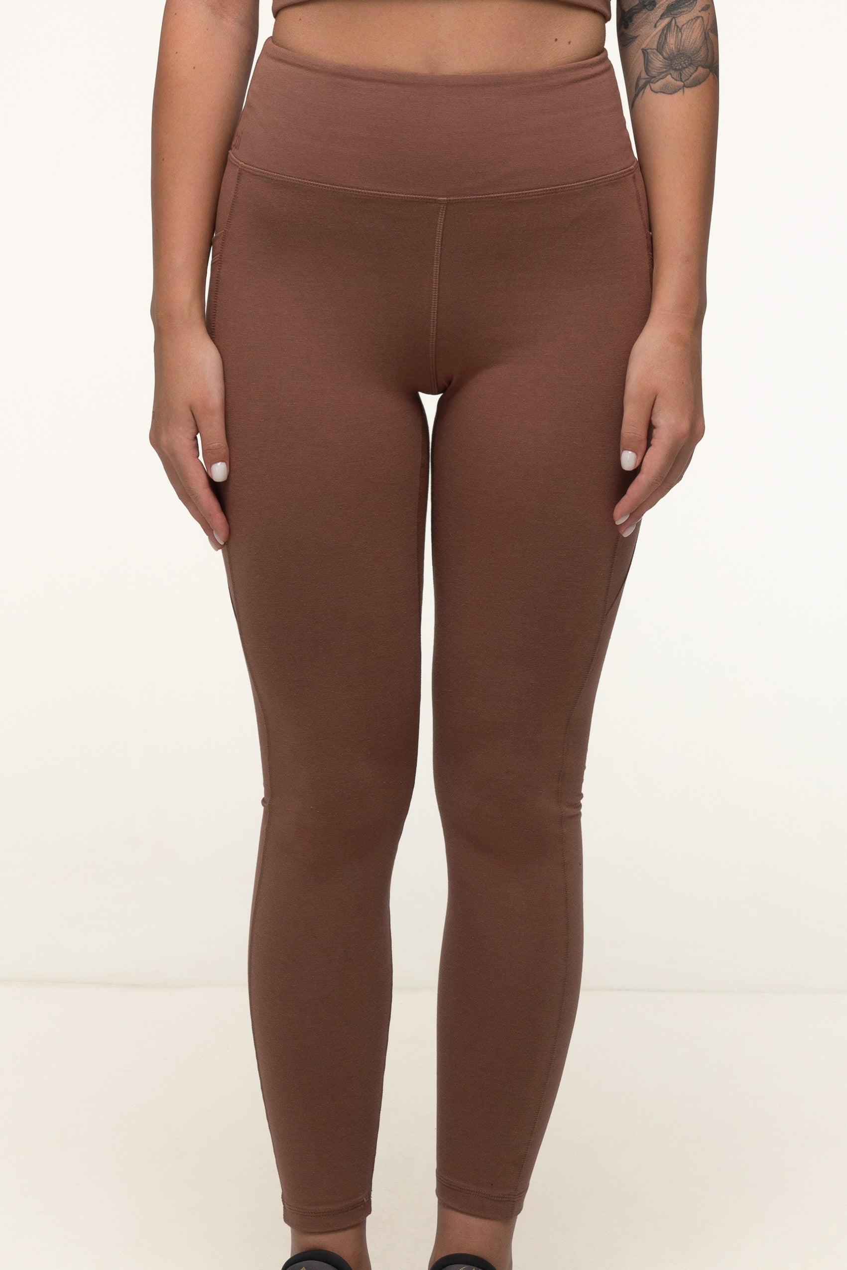 Closeup of a woman in a cappuccino brown eco-friendly high rise bamboo leggings with pockets. #color_brown