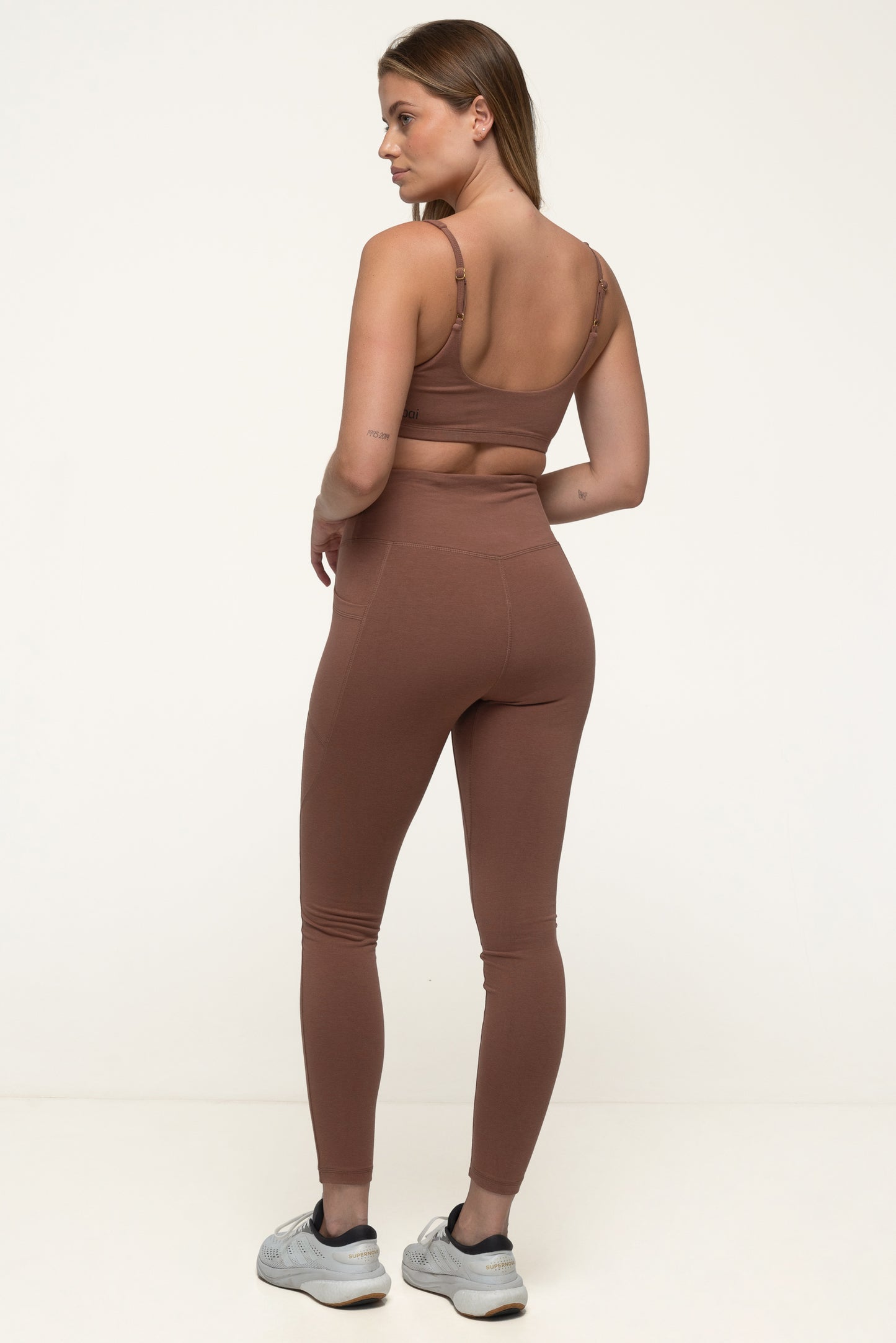 A woman in a cappuccino brown sustainable activewear set wearing high rise soft leggings and an eco yoga top. #color_brown