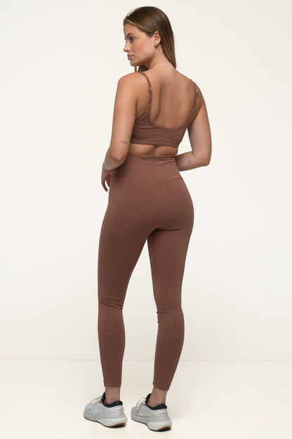 A woman in a cappuccino brown sustainable activewear set wearing high rise soft leggings and an eco yoga top. #color_brown