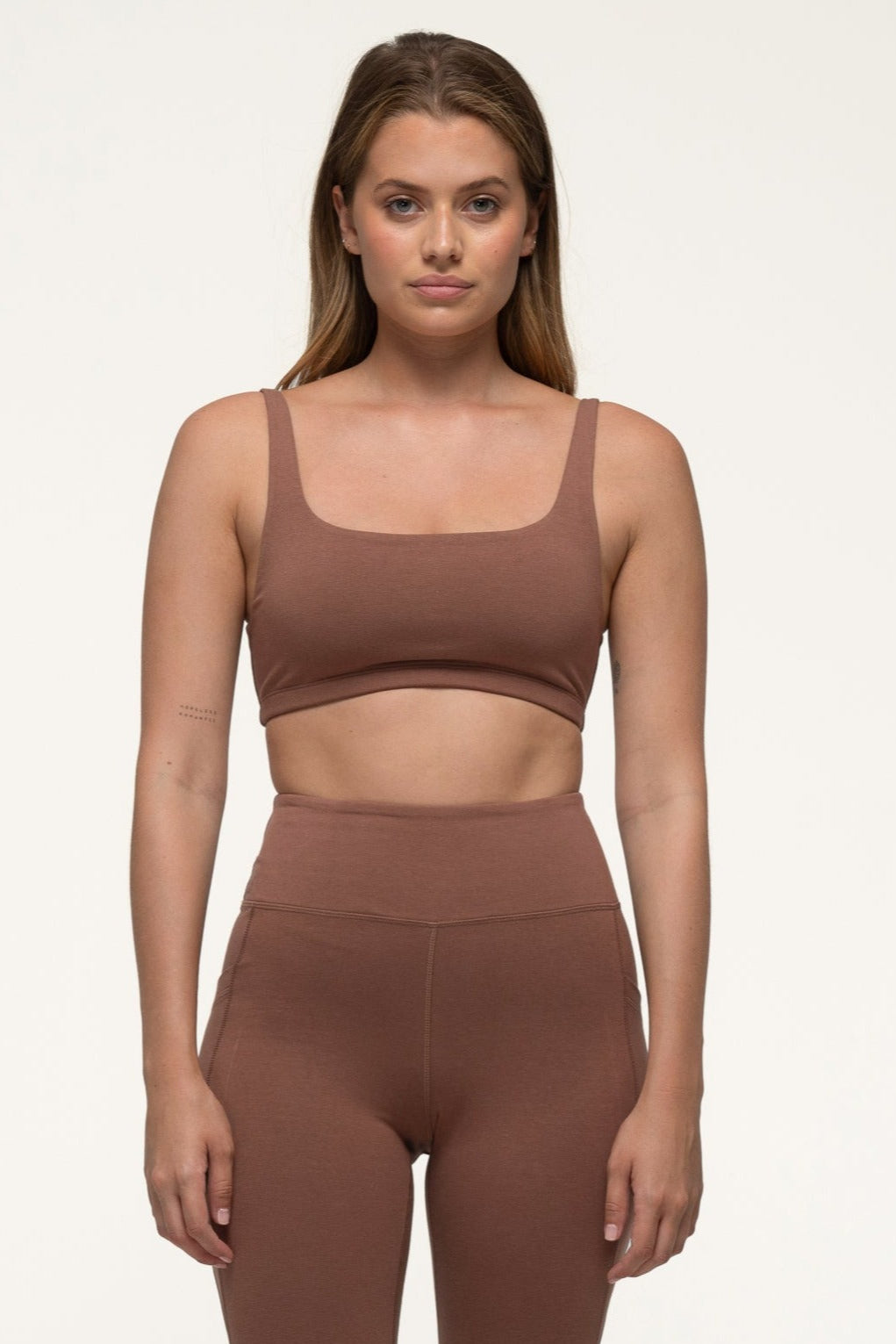 A woman in a cappuccino brown sustainable activewear set wearing high rise bamboo leggings with pockets and an eco exercise top. #color_CappuccinoBrown