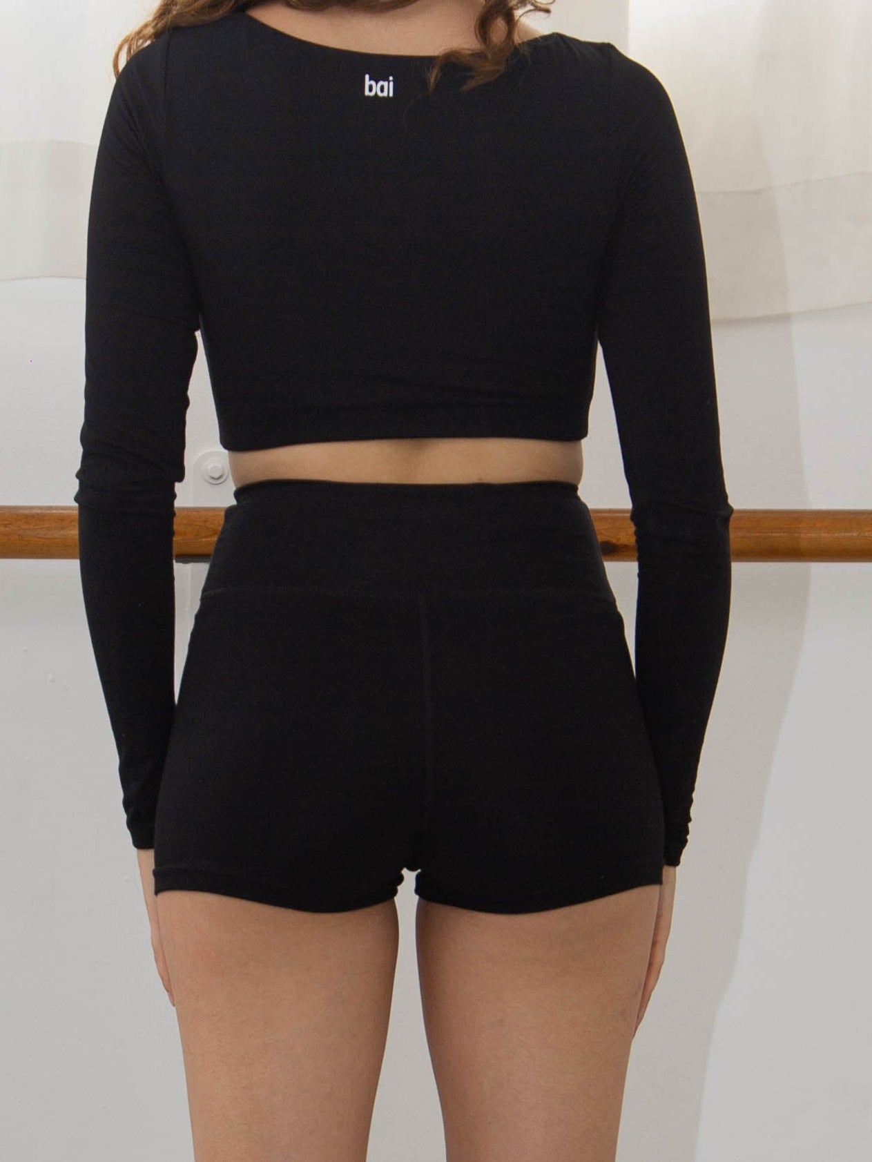 Woman wearing black modal shorts in a dance studio that end just above her bottom