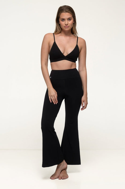 Woman wearing a black yoga set with matching pants on a white background