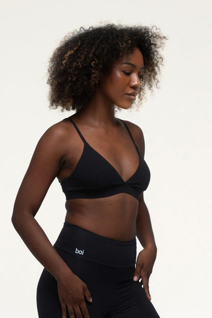 Woman wearing a black sports bra and leggings on a white background