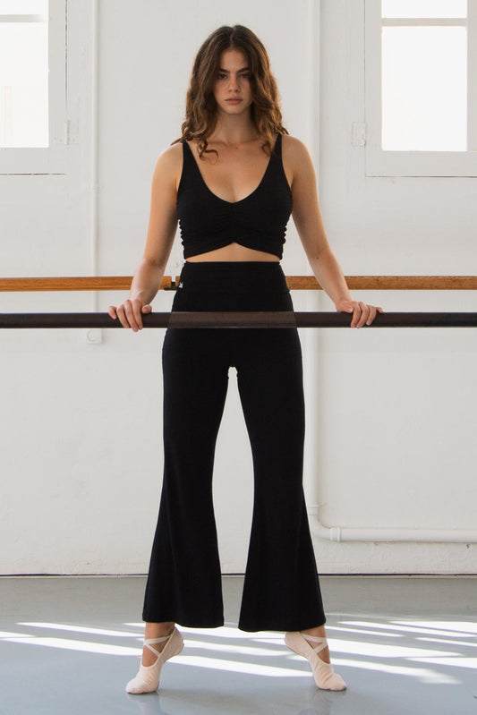 Woman practicing ballet in a studio doing barre in black flare pants
